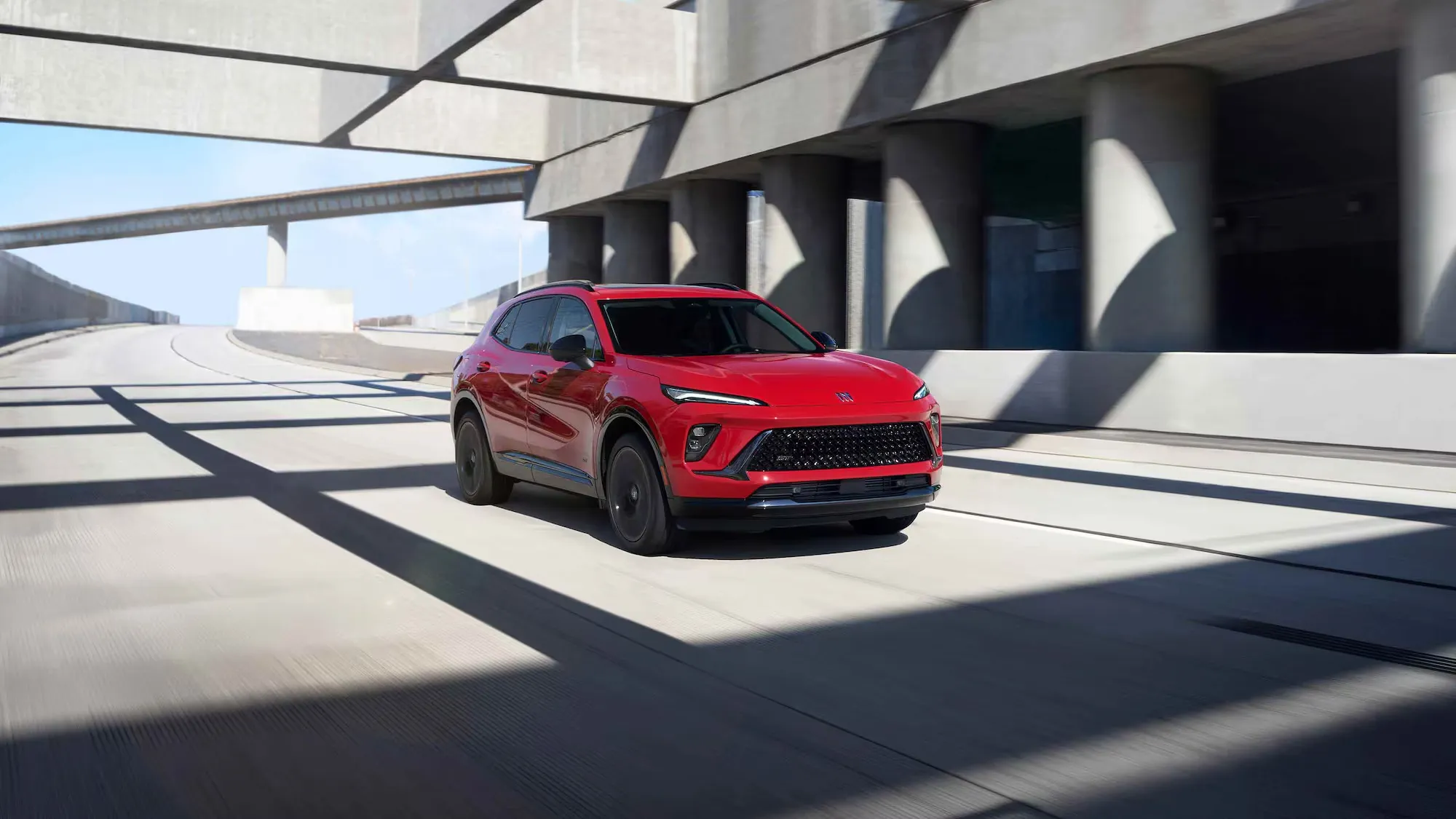 Buick Envision 2026 rouge circulant dans un environnement urbain moderne.