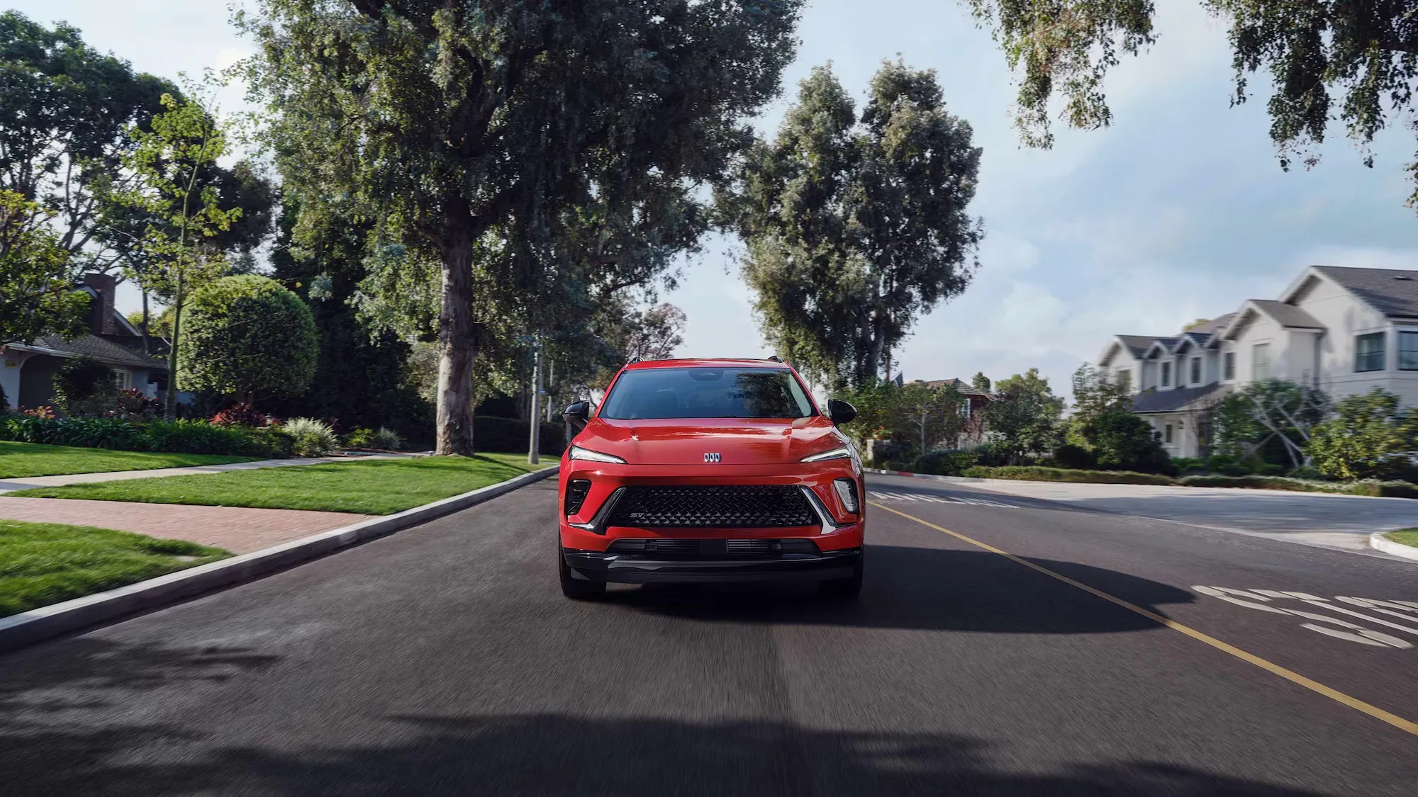 Buick Envision 2026 rouge vu de face sur une route de banlieue.