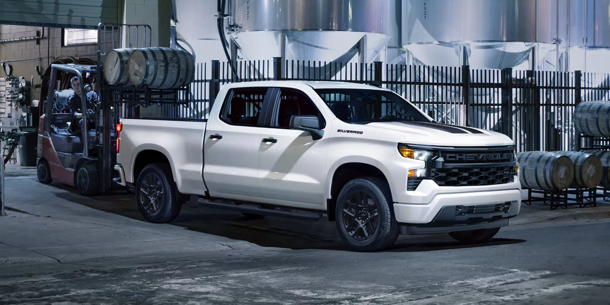 Chevrolet Silverado 1500 2026 blanc utilisé sur un site de travail industriel avec un chariot élévateur.