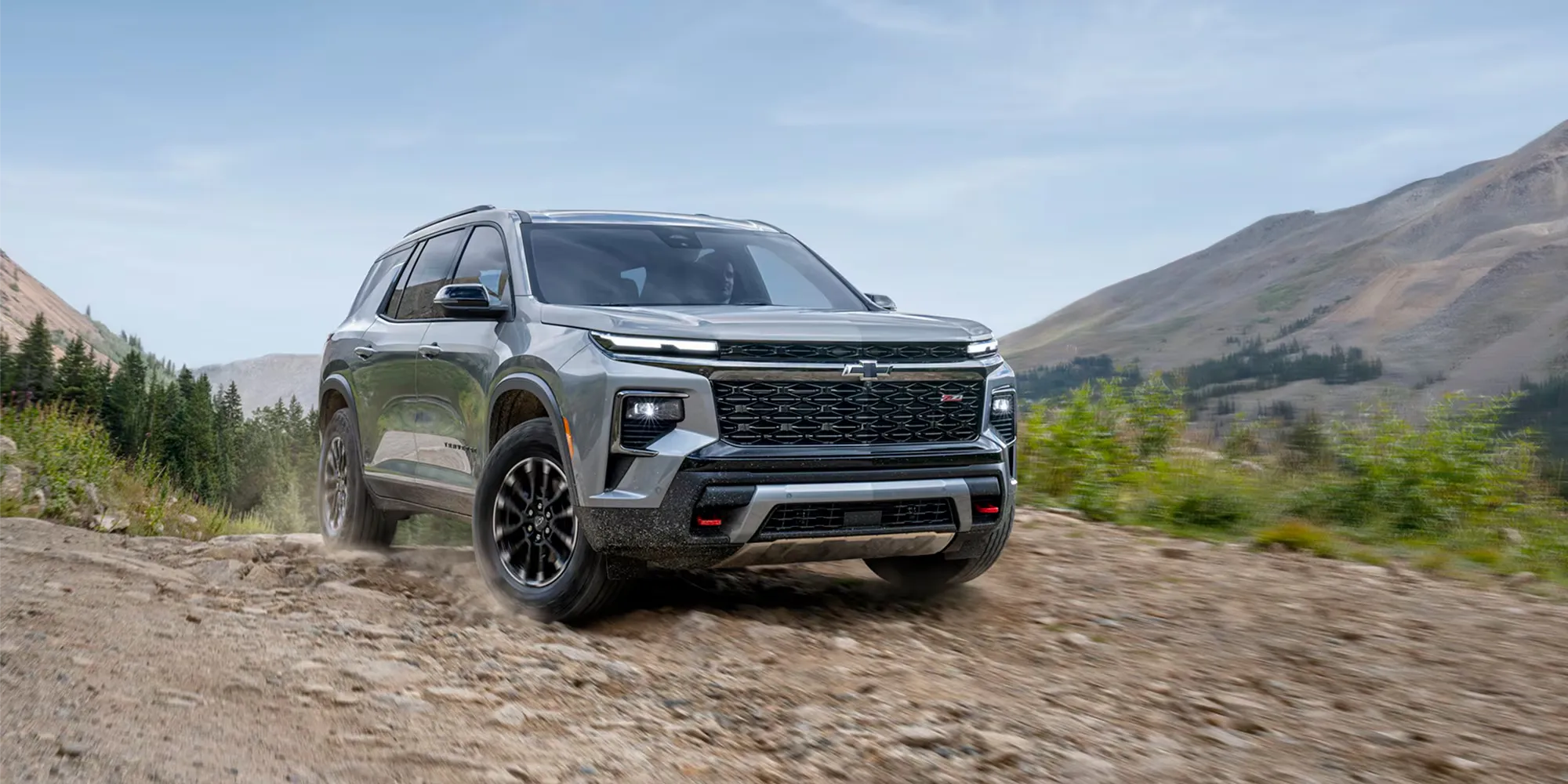 Chevrolet Traverse 2026 gris circulant sur un chemin rocailleux en montagne.