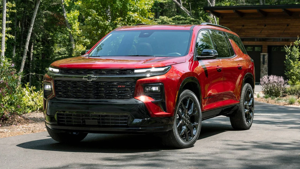 Chevrolet Traverse 2026 rouge stationné devant une maison, vu de trois quarts avant.
