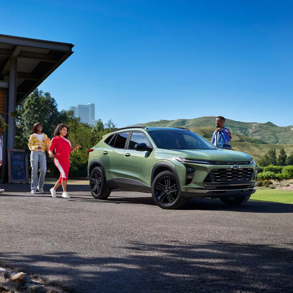 Chevrolet Trax 2026 vert stationné à l’extérieur près de deux passagers.