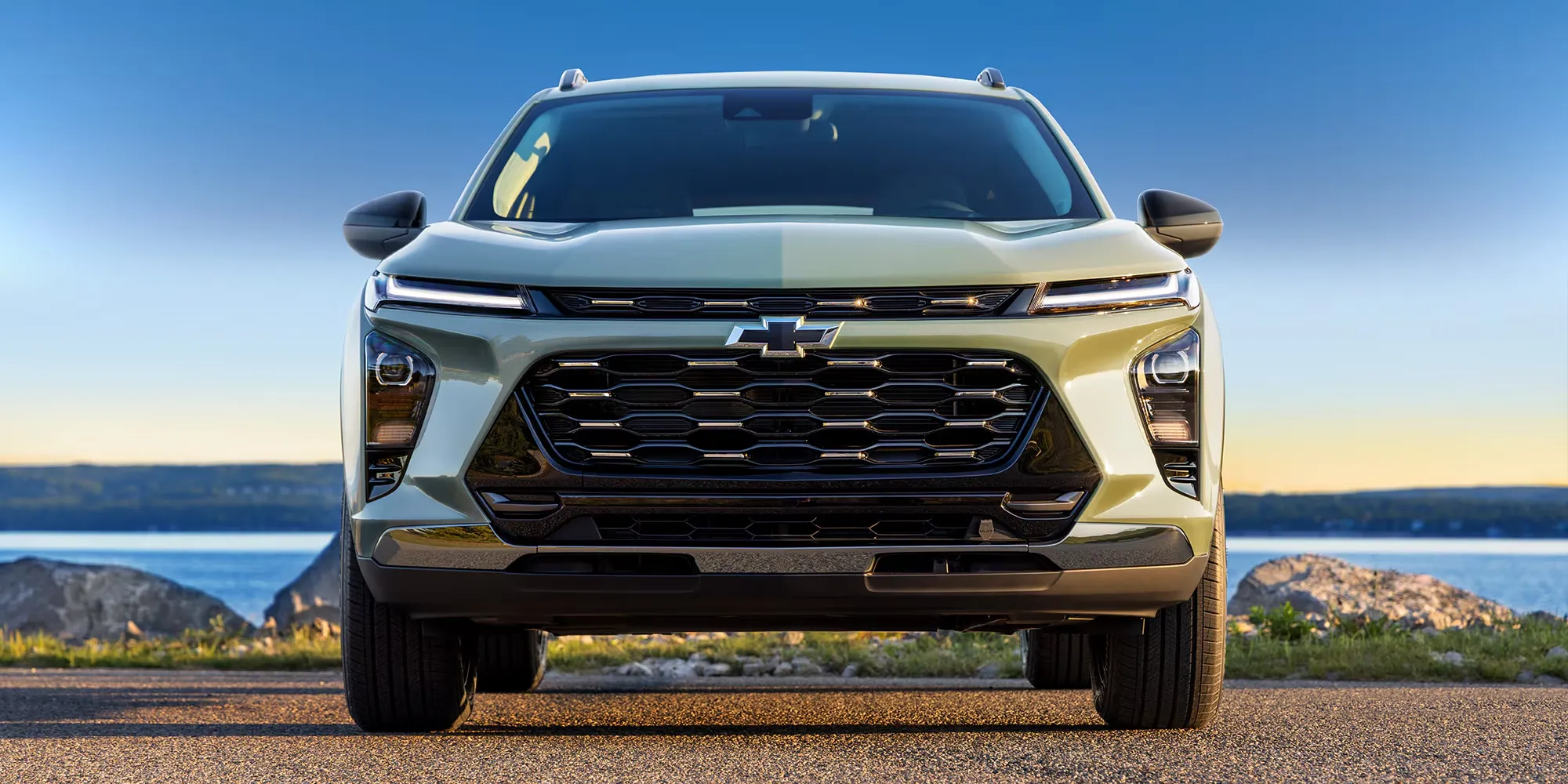 Chevrolet Trax 2026 vu de face dans un paysage dégagé au coucher du soleil.