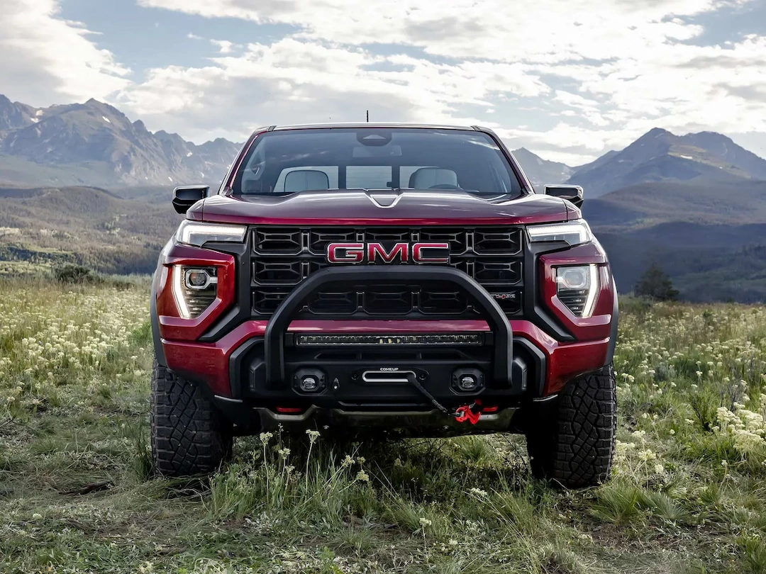 GMC Canyon 2026 rouge vu de face dans un paysage de montagne.