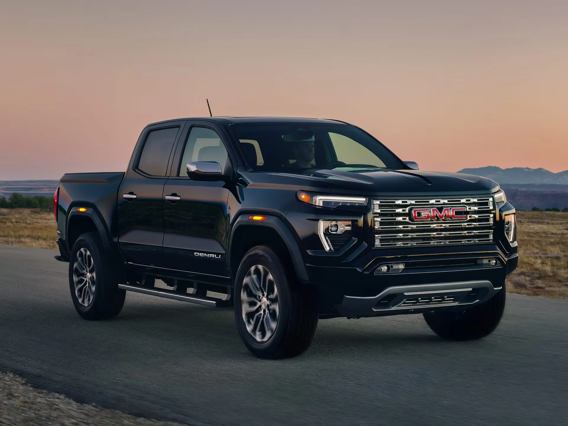 GMC Canyon 2026 noir stationné au coucher du soleil sur une route.