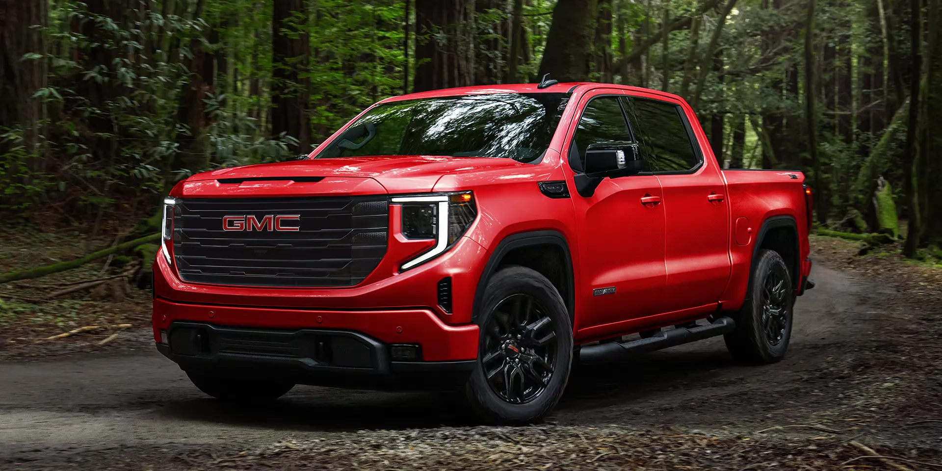 GMC Sierra 1500 2026 rouge stationné en forêt pour illustrer les pickups disponibles chez Lussier GM.
