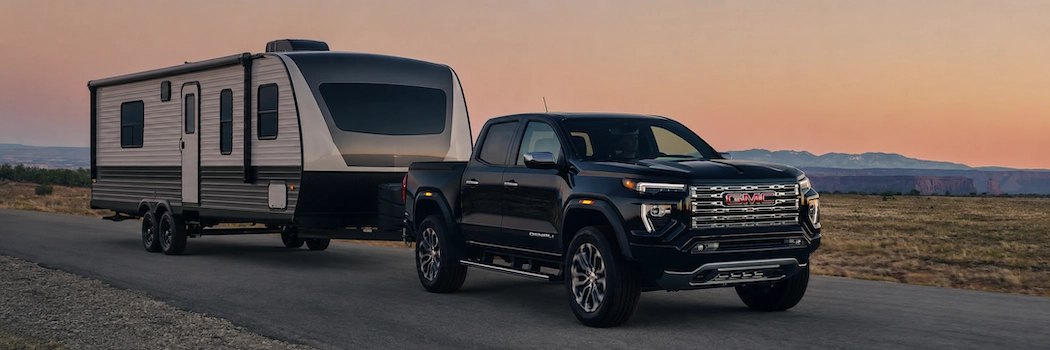GMC Canyon 2026 noir remorquant une roulotte pour illustrer sa capacité de remorquage.