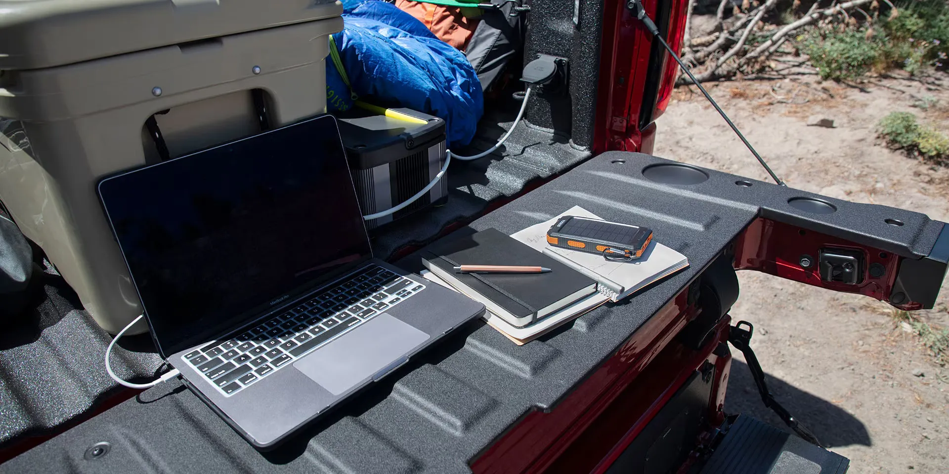 Caisse du GMC Sierra 1500 2026 aménagée avec équipement de camping et ordinateur.